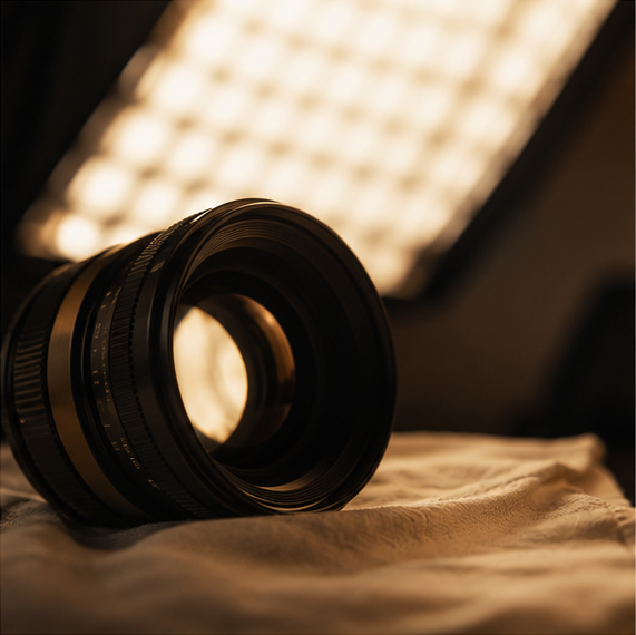 A prime camera lens lit by a softbox, warm and low-key