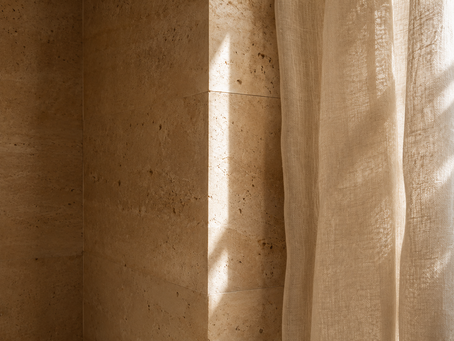 A travertine wall and linen drape in warm directional light